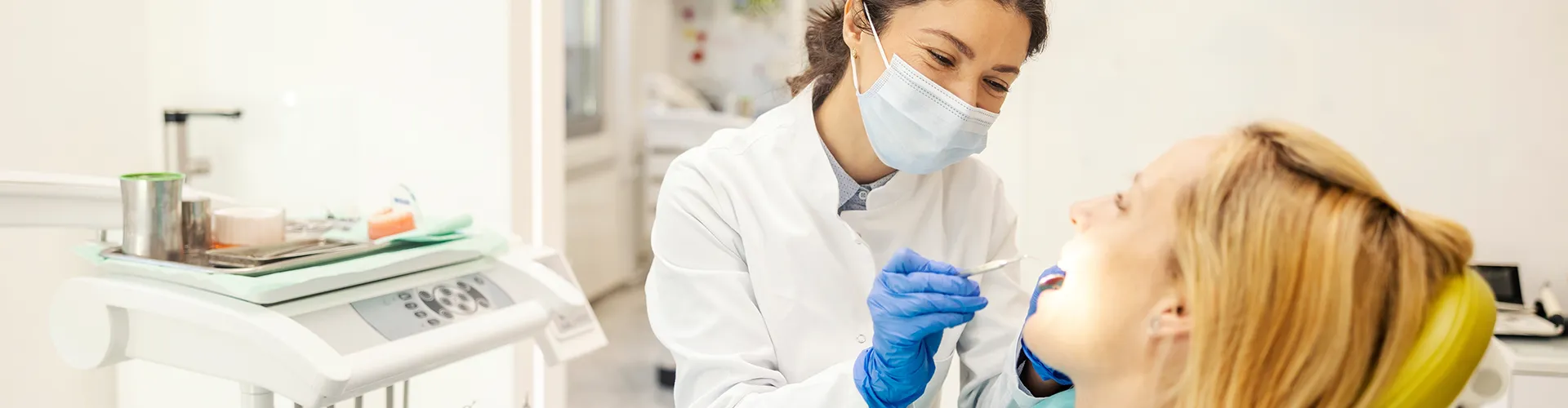 dentist wearing mask using dental tool in patient's mouth