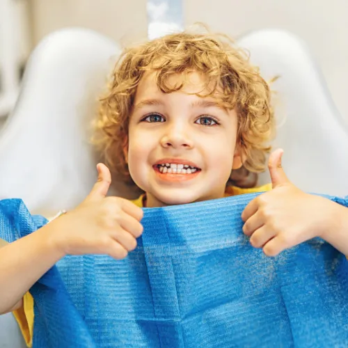 Smiling boy giving thumbs-up with both hands.