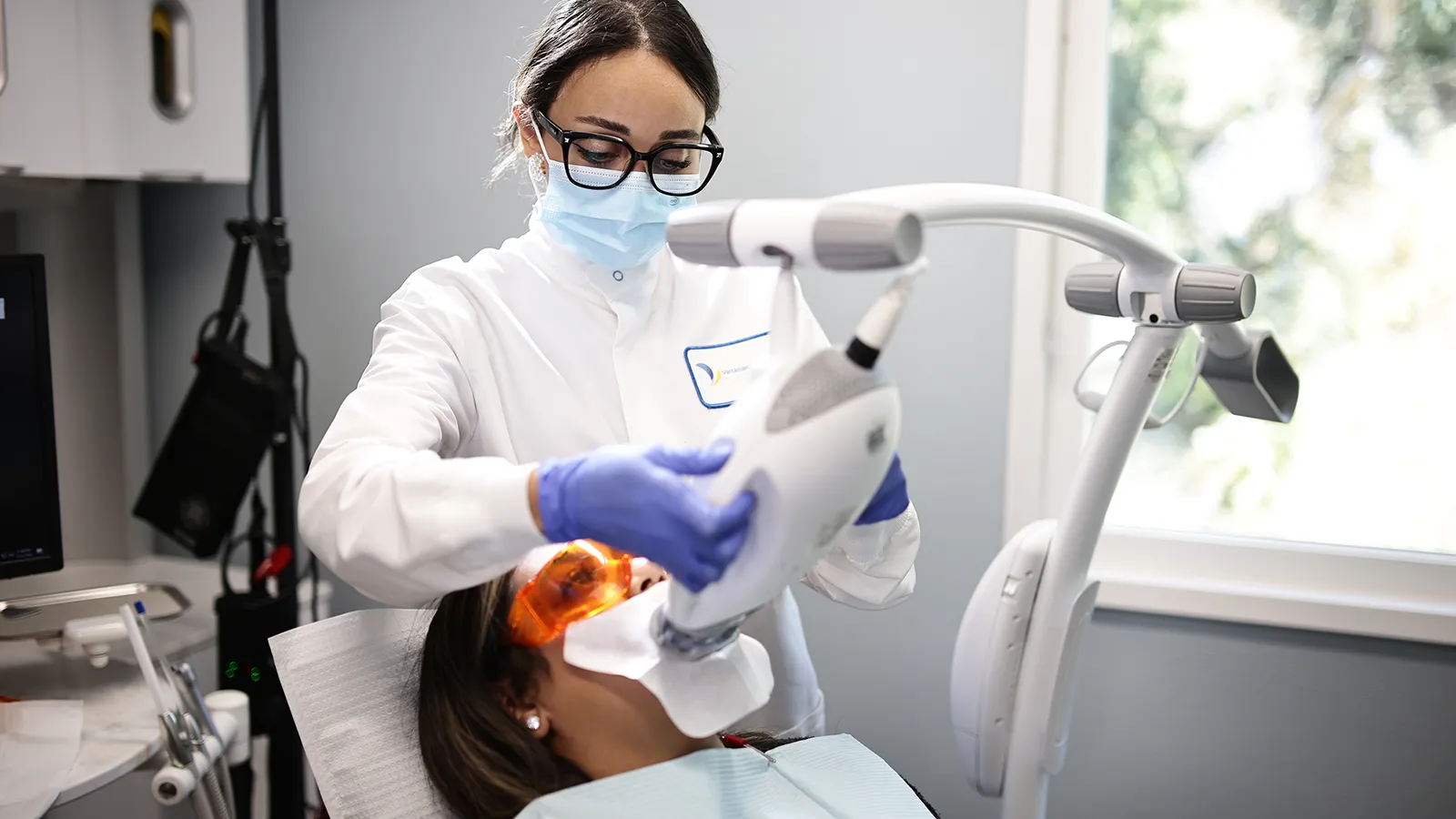 Patient receiving a teeth whitening treatment from her dentist.