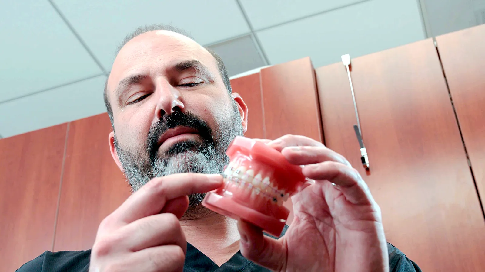 Dr. James Vartanian showing a teeth model with braces.