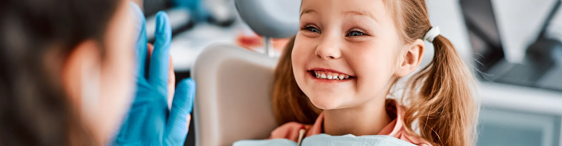 smiling child holding bunny looking at dentist